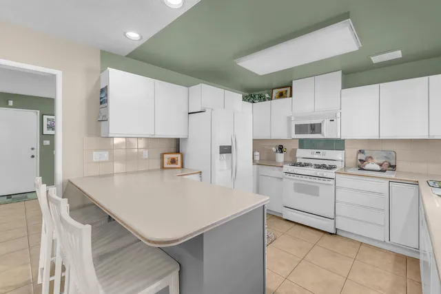 a kitchen with a sink a white cabinets and white appliances