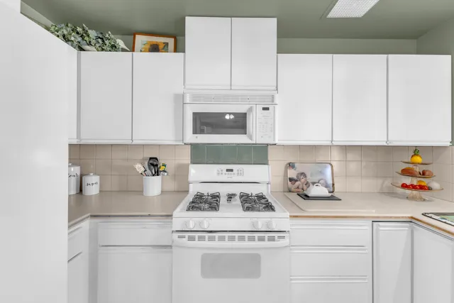 a kitchen with granite countertop white cabinets and white appliances