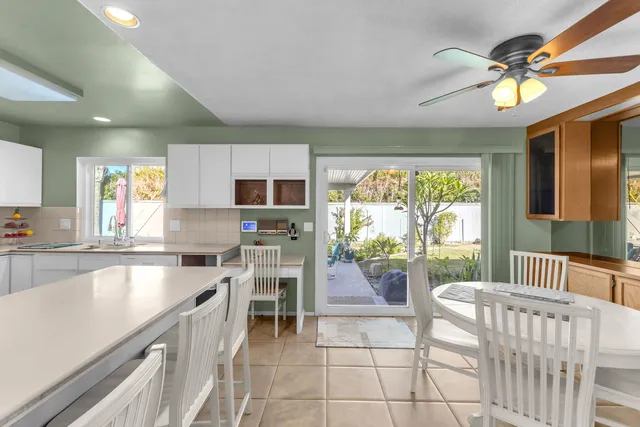 a kitchen with stainless steel appliances granite countertop a refrigerator a sink a stove top oven and a dining table with wooden floor