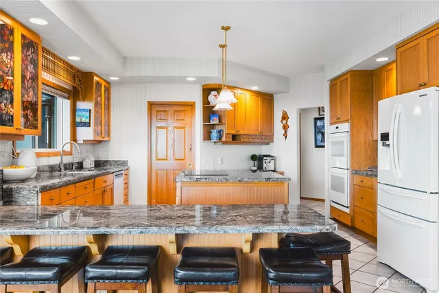 a kitchen with stainless steel appliances granite countertop a refrigerator a stove and a sink