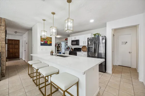 a large kitchen with stainless steel appliances kitchen island granite countertop a table chairs and a refrigerator