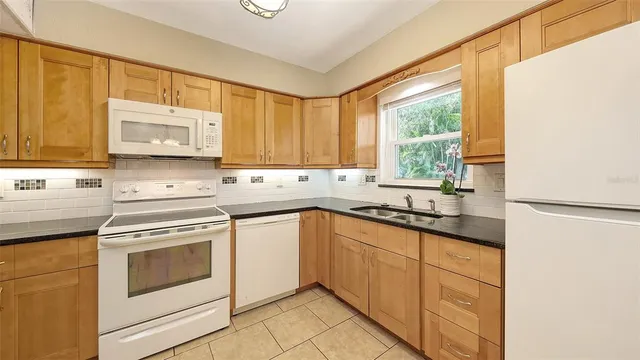 a kitchen with granite countertop cabinets stainless steel appliances a sink and a window