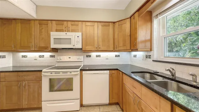 a kitchen with granite countertop a sink a stove and cabinets
