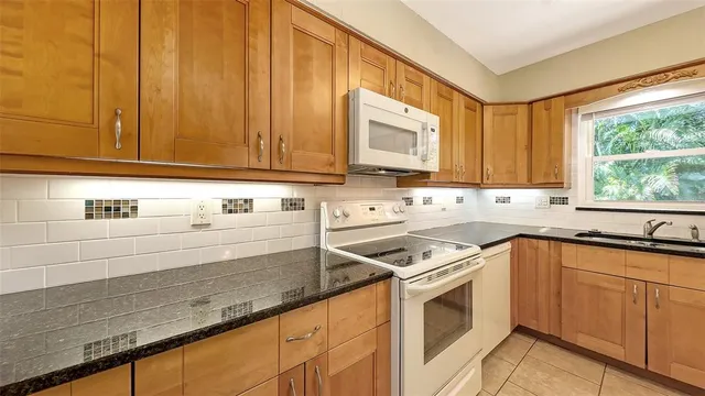 a kitchen with granite countertop cabinets stainless steel appliances a sink and a window