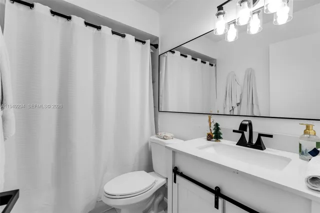 a bathroom with a sink a mirror a light and a toilet