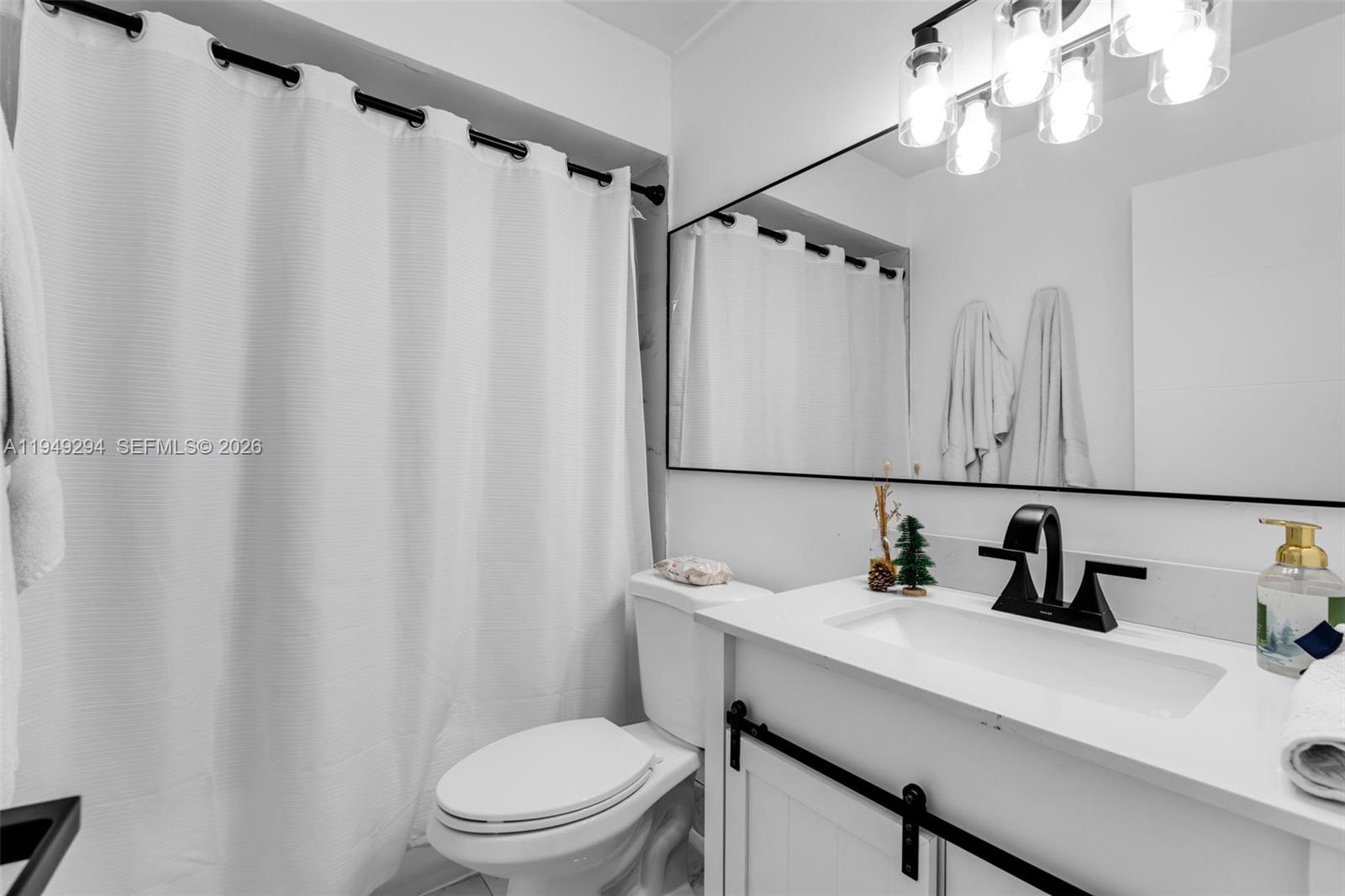 12909 Southwest 64th Lane Miami, FL 33183 - Photo 16 of 35 a bathroom with a sink a mirror a light and a toilet