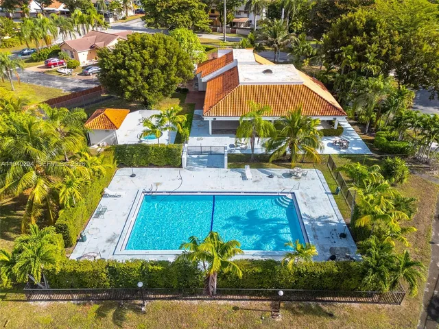 an aerial view of a house with swimming pool and large trees
