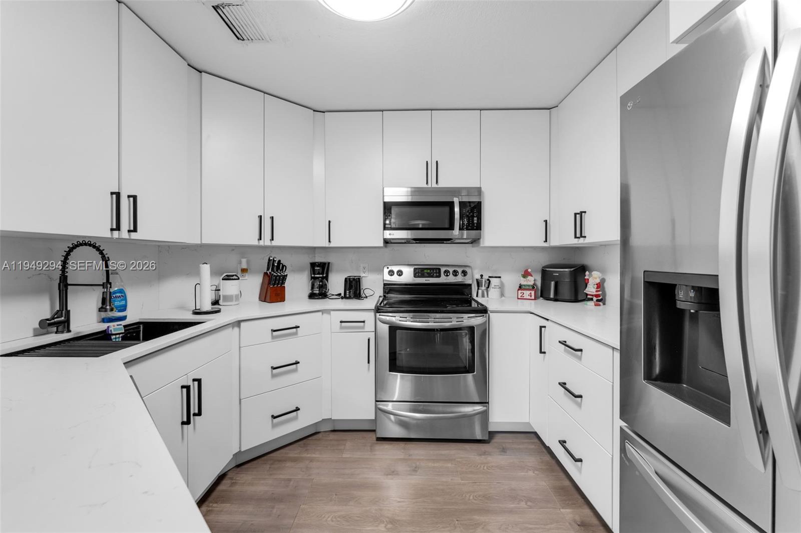 12909 Southwest 64th Lane Miami, FL 33183 - Photo 6 of 35 a kitchen with granite countertop white cabinets and stainless steel appliances