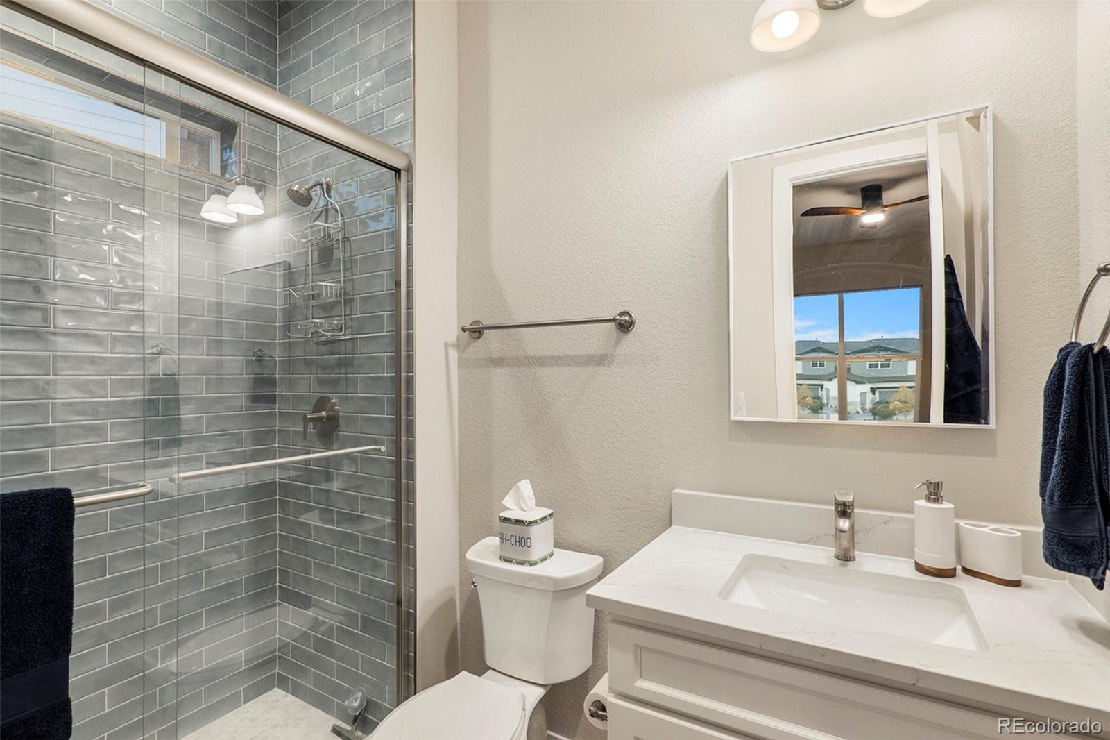 5828 Tesoro Point Parker, CO 80134 - Photo 22 of 43 a bathroom with a granite countertop sink toilet a mirror and shower