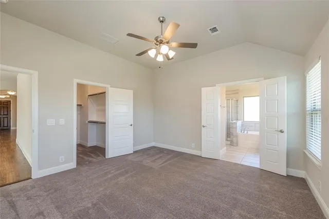 a view of an empty room with a chandelier fan and a window