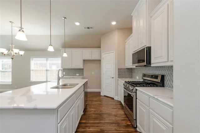 a kitchen with kitchen island a sink stainless steel appliances and cabinets