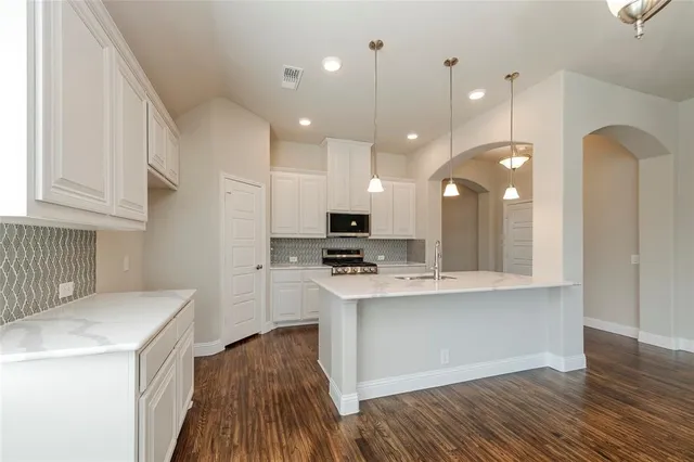 a kitchen with kitchen island granite countertop a sink cabinets and stainless steel appliances