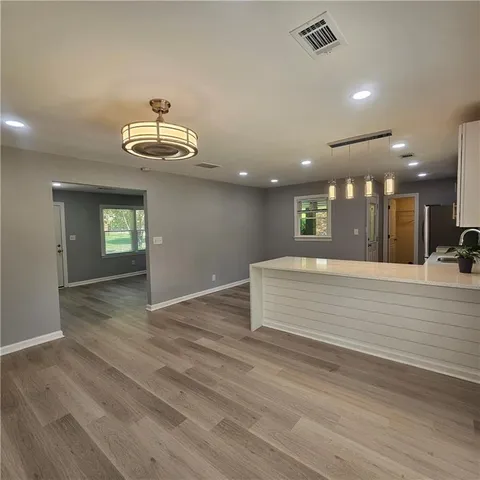 an empty room with wooden floor and kitchen view