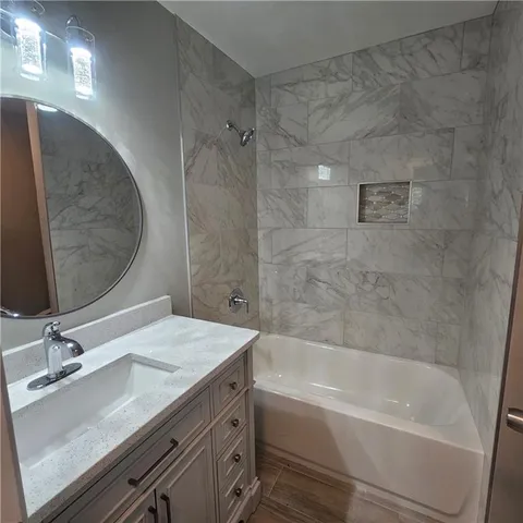 a bathroom with a granite countertop sink a mirror and bathtub