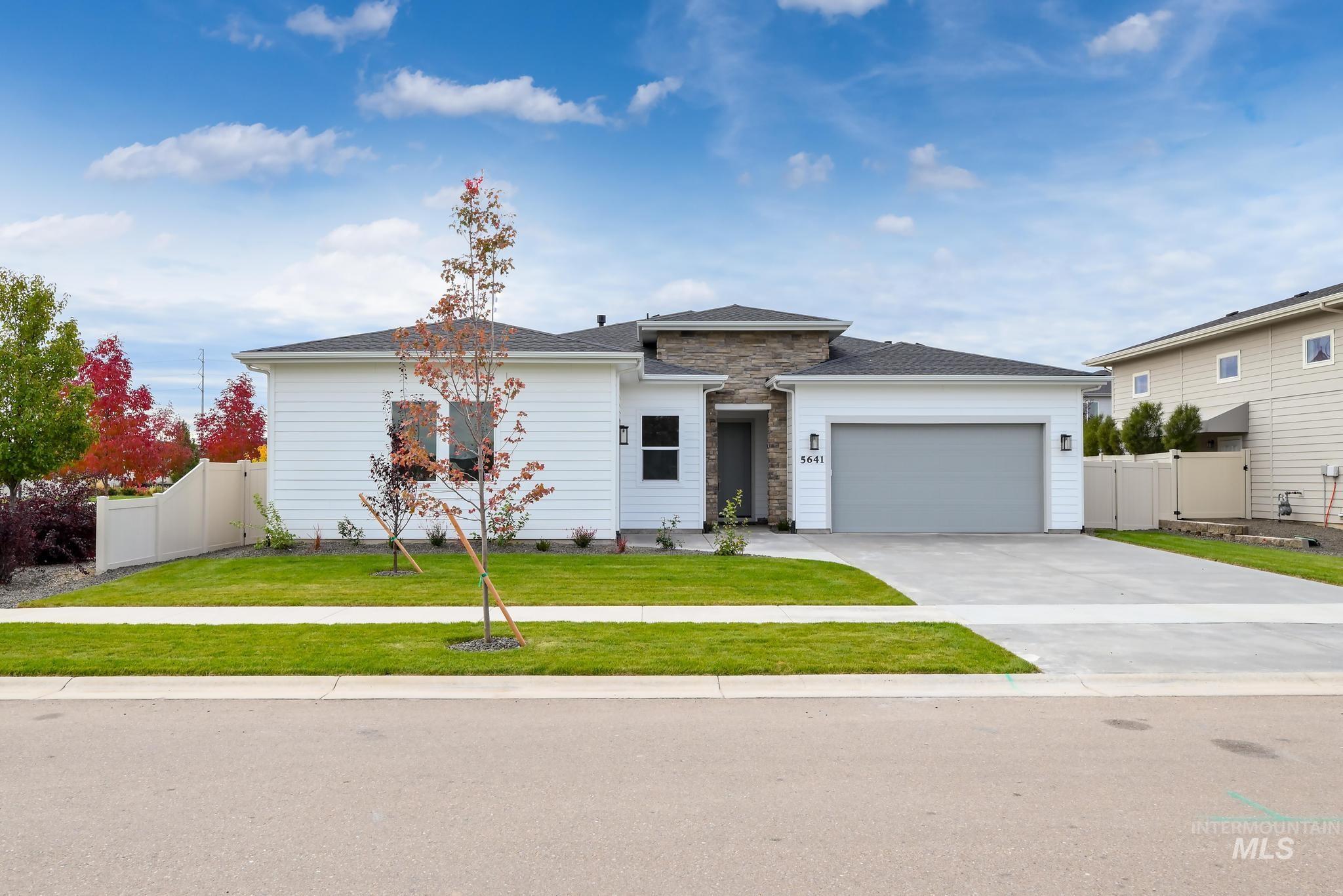 View of front facade with concrete driveway, an attached garage, stone siding, and a gate