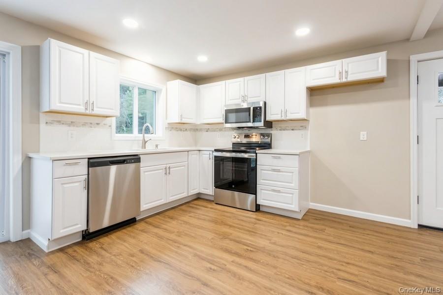 435 State Rte 55 Eldred, NY 12732 - Photo 11 of 26 a kitchen with stainless steel appliances granite countertop a stove top oven a sink dishwasher and a refrigerator with wooden floor