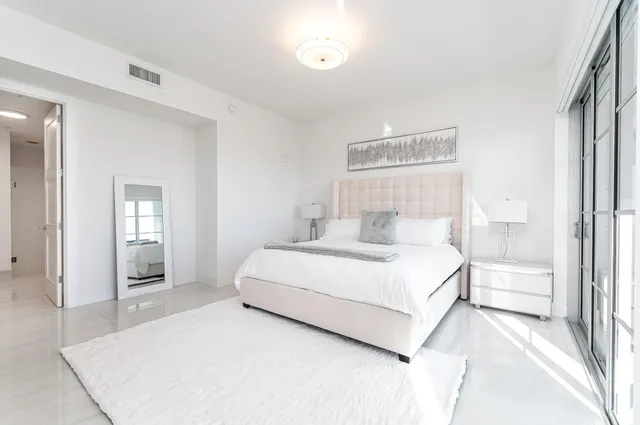 a bedroom with a white bed and a large mirror