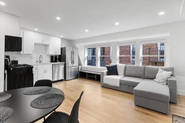a living room with furniture a kitchen view and a refrigerator