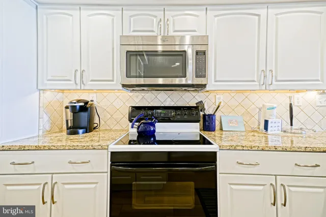 a kitchen with granite countertop white cabinets and stainless steel appliances