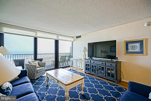 a living room with furniture a flat screen tv and a floor to ceiling window