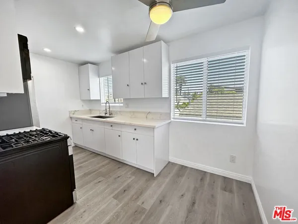 a kitchen with a stove a sink wooden floor and a window