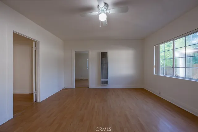 a view of empty room with wooden floor and fan