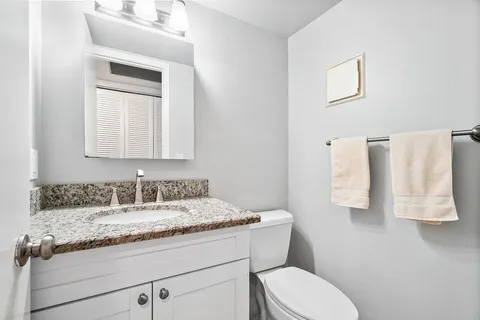 a bathroom with a granite countertop toilet sink and mirror