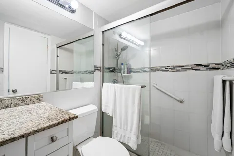 a bathroom with a granite countertop sink mirror vanity and toilet