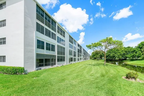 a view of an apartment with a big yard and large trees