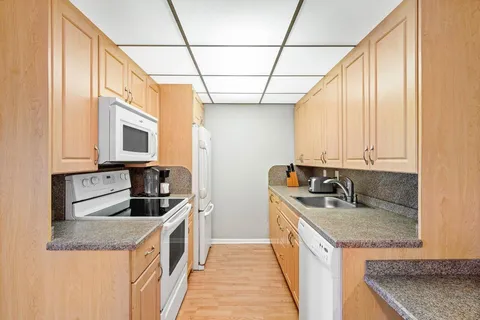 a kitchen with stainless steel appliances granite countertop a sink a stove and a wooden cabinets