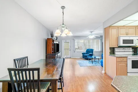 a view of a dining room and livingroom with furniture wooden floor a chandelier
