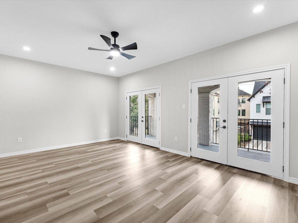 1319 West Bell Street Houston, TX 77019 - Photo 21 of 50 This spacious, primary bright room features light vinyl flooring, modern recessed lighting, and a ceiling fan. Large double French doors open to a private balcony, providing ample natural light and an inviting view.