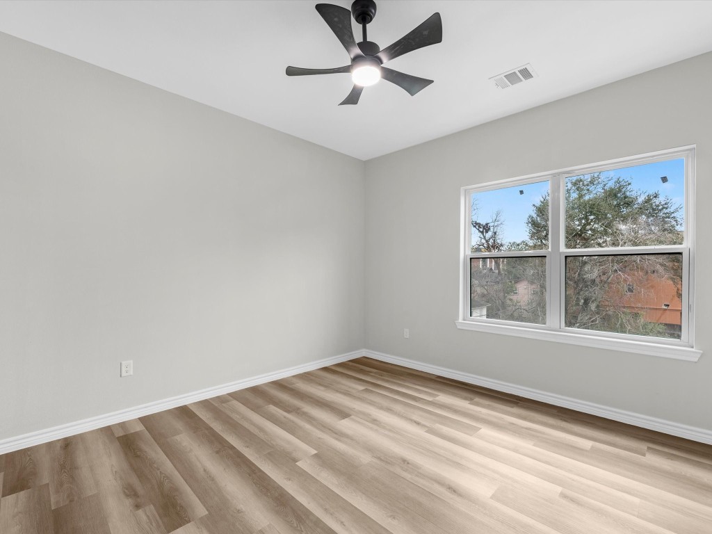 1319 West Bell Street Houston, TX 77019 - Photo 38 of 50 This room features fresh, neutral walls and vinyl flooring, creating a bright and airy space. It includes a modern ceiling fan and a large window, offering plenty of natural light and a view of greenery outside.