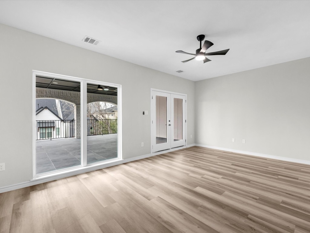 1319 West Bell Street Houston, TX 77019 - Photo 42 of 50 Open game room with light vinyl flooring, featuring double doors leading to an expansive terrace. Ceiling fan and recessed lighting enhance the modern feel, offering a view of neighboring homes.