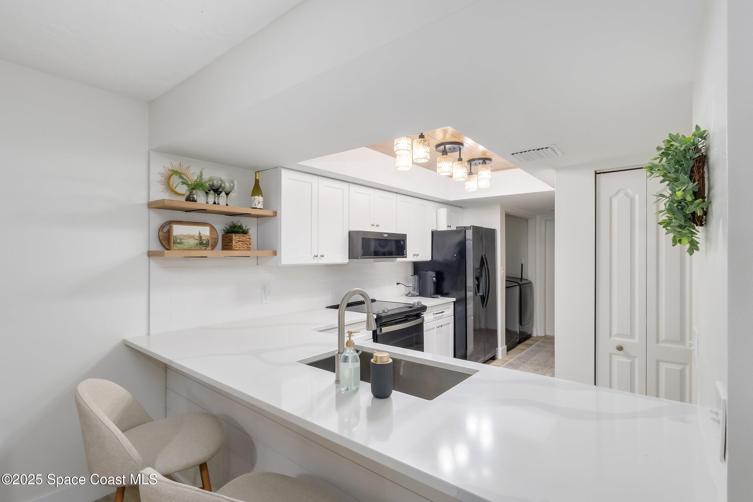 24 Olive Street Cocoa Beach, FL 32931 - Photo 15 of 50 a kitchen with stainless steel appliances kitchen island granite countertop a sink and cabinets
