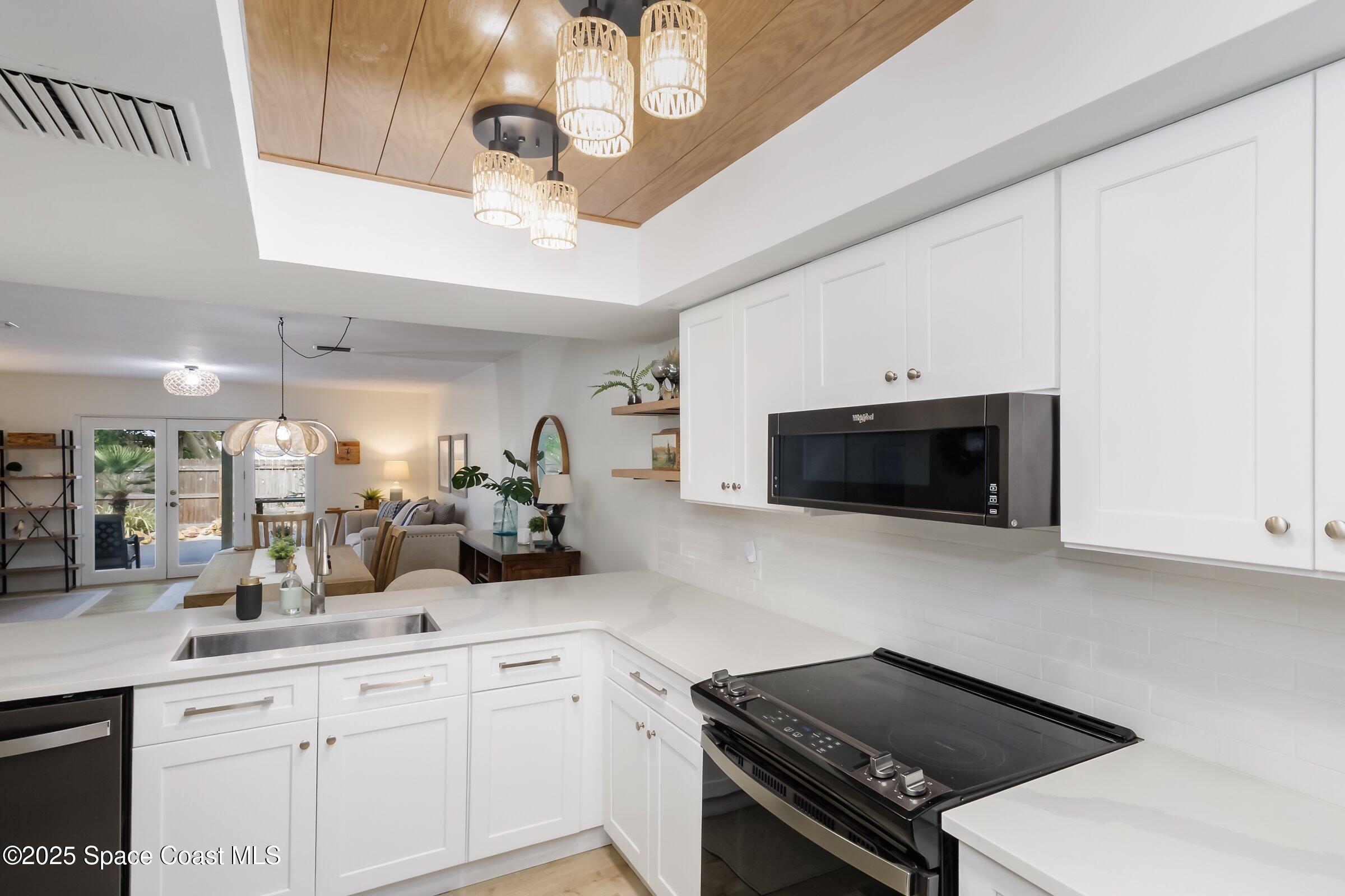 24 Olive Street Cocoa Beach, FL 32931 - Photo 17 of 50 a kitchen with stainless steel appliances a stove a sink a microwave and cabinets