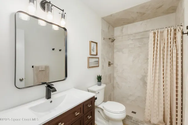 a bathroom with a sink a toilet a mirror and shower