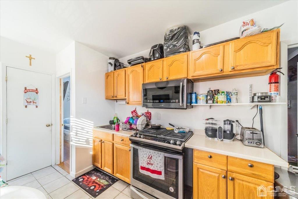 28 Union Street Carteret, NJ 07008 - Photo 9 of 25 a kitchen with stainless steel appliances granite countertop a stove a sink and a microwave