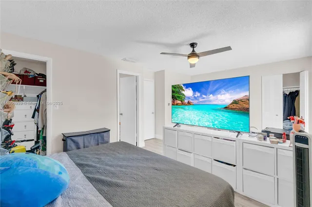 a bedroom with a bed mirror on the wall and a flat screen tv