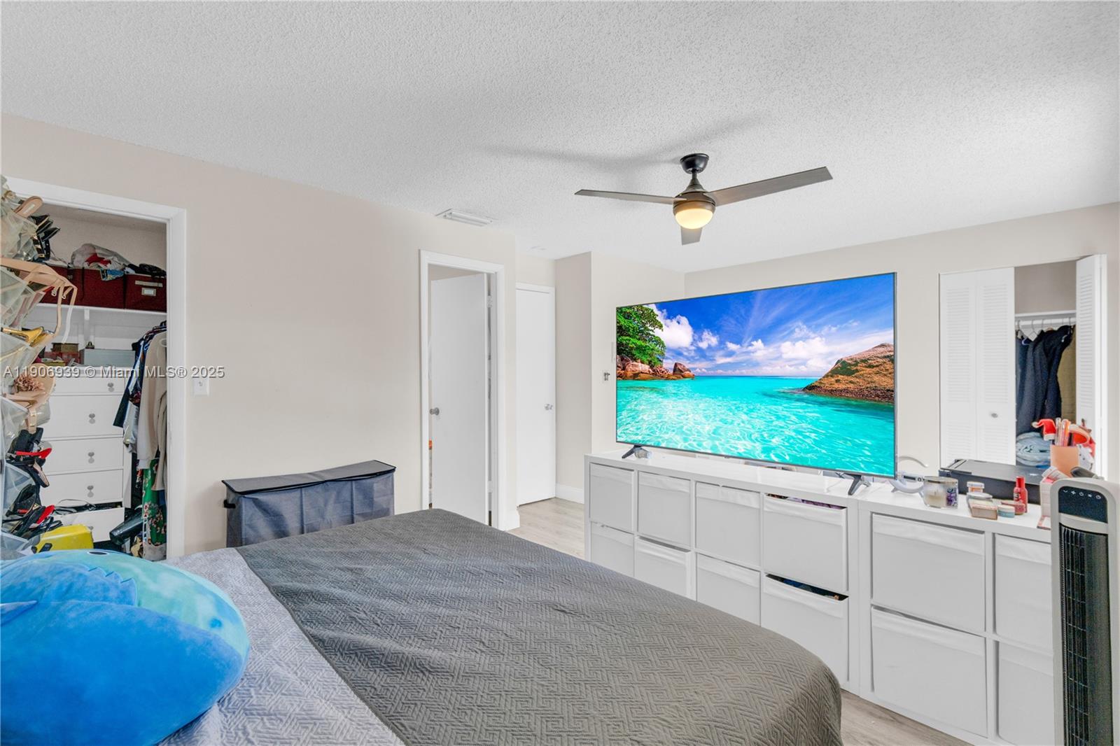 13715 Southwest 84th Street, Unit F Miami, FL 33143 - Photo 21 of 30 a bedroom with a bed mirror on the wall and a flat screen tv