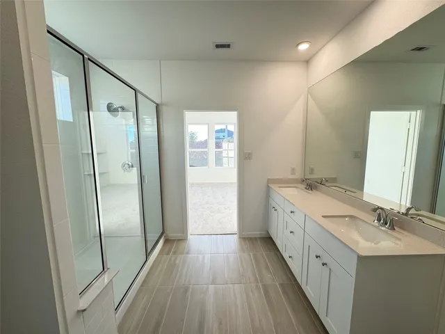 a spacious bathroom with a double vanity sink a large mirror a shower and a bathtub