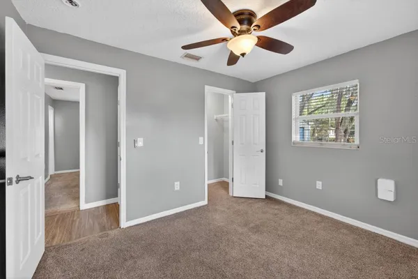 a view of a big room with windows and ceiling fan
