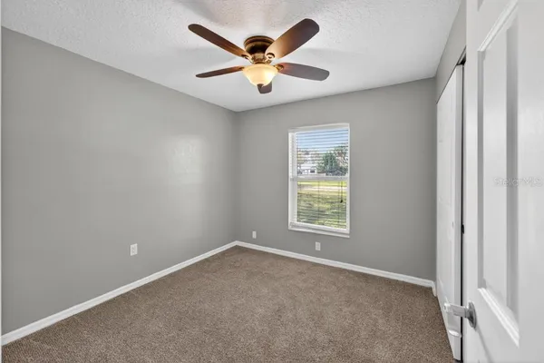 an empty room with ceiling fan and window