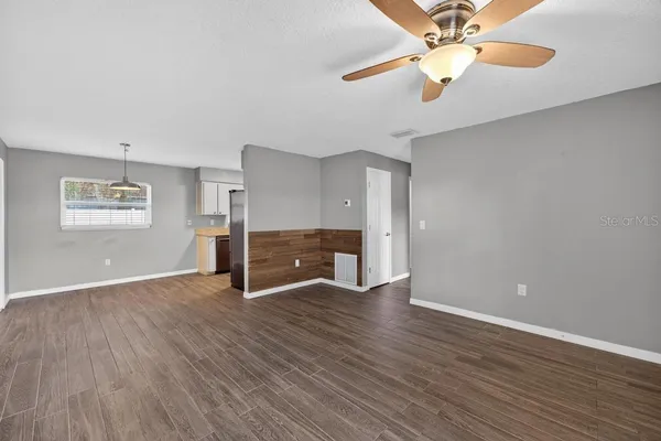an empty room with wooden floor fan and windows
