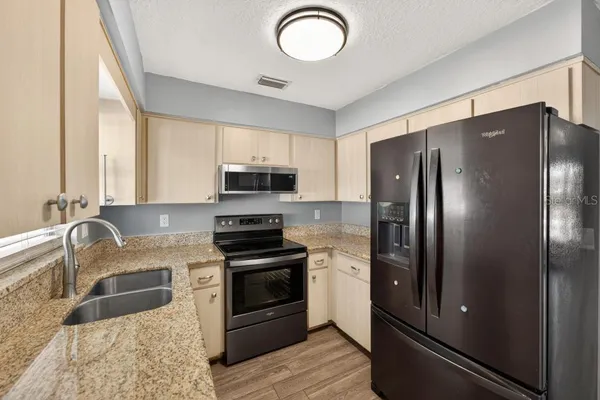 a kitchen with stainless steel appliances granite countertop a refrigerator sink and stove