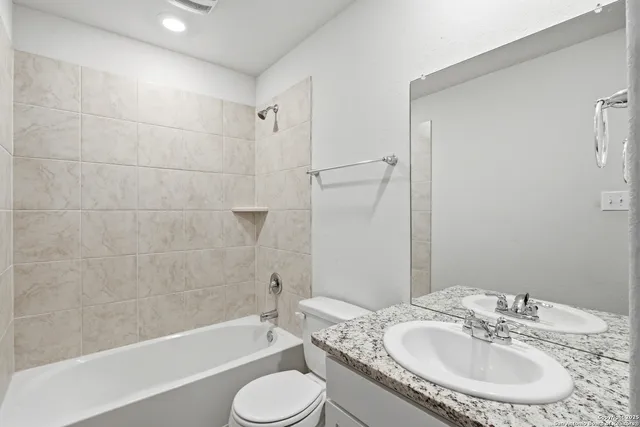 a bathroom with a granite countertop sink toilet tub and shower
