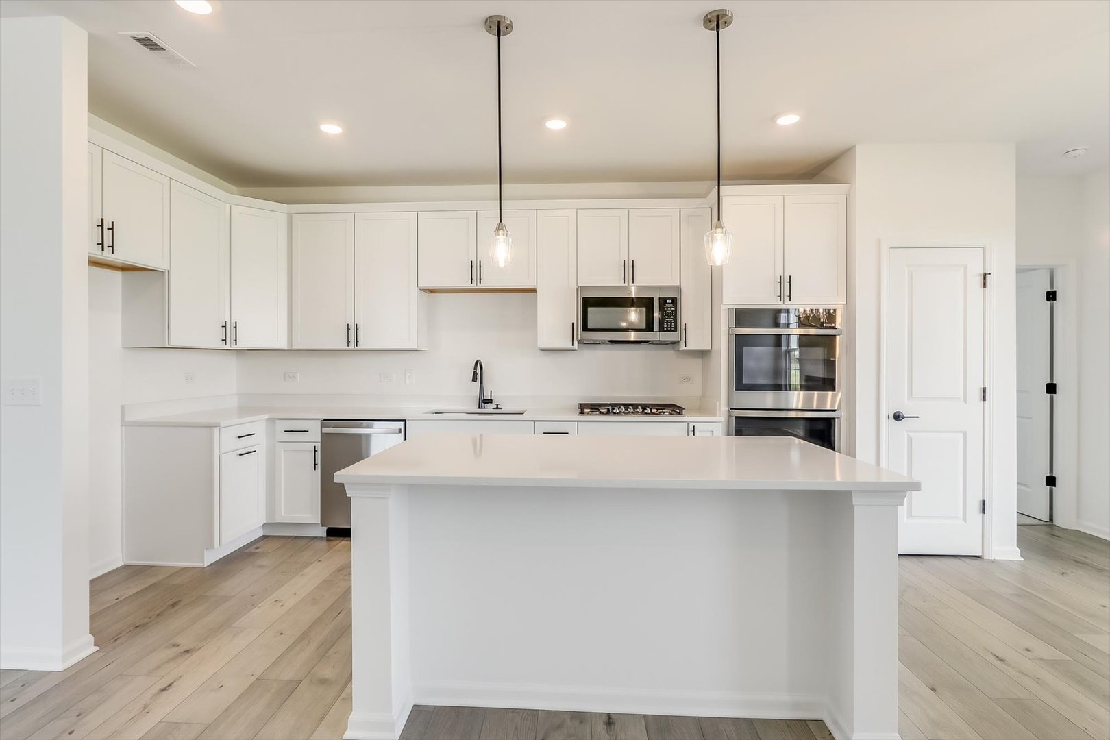 730 Alberta Avenue Oswego, IL 60543 - Photo 15 of 29 a kitchen with kitchen island a stove a sink a refrigerator and white cabinets with wooden floor