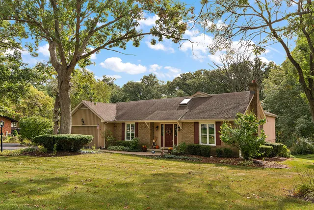 a front view of a house with a garden and trees