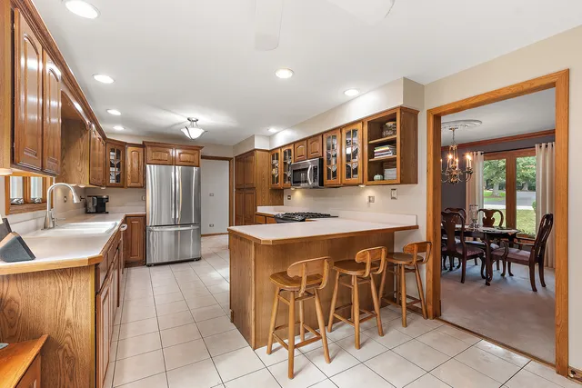 a kitchen with stainless steel appliances granite countertop a stove top oven a sink a dining table and chairs with wooden floor