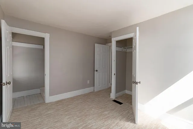 a view of an empty room with closet and wooden floor